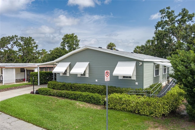 6710 36th Ave E Unit 114, Palmetto, FL 34221 - view of side of property featuring a yard, concrete driveway, and a carport