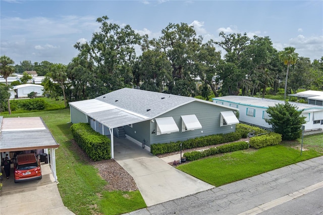 6710 36th Ave E Unit 114, Palmetto, FL 34221 - view of front of property featuring a carport, concrete driveway, a front yard, and view of wooded area