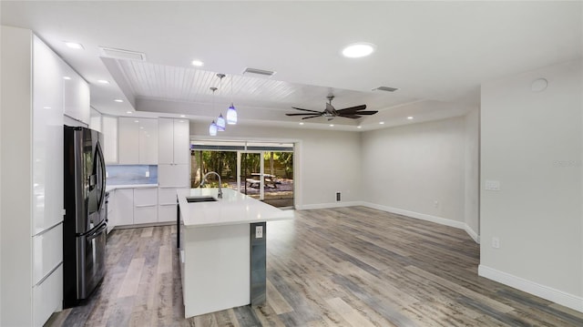 3525 Riviera Dr, Sarasota, FL 34232 - kitchen with modern cabinets, black fridge, white cabinets, a ceiling fan, and light wood-type flooring