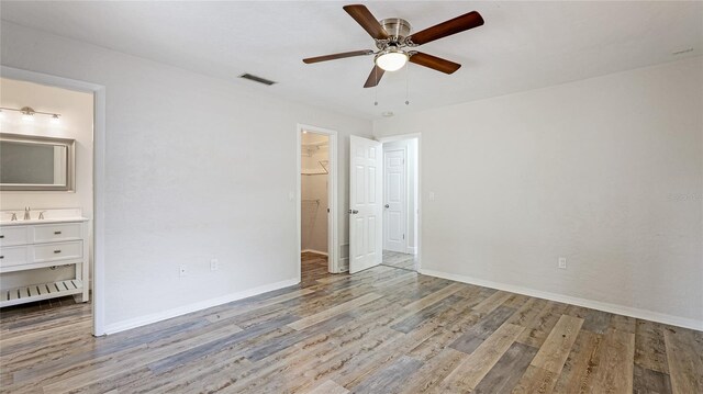 3525 Riviera Dr, Sarasota, FL 34232 - unfurnished bedroom with wood finished floors, a walk in closet, ensuite bath, ceiling fan, and a closet