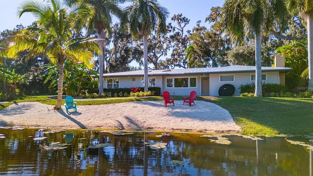 5311 36th Ave E, Palmetto, FL 34221 - rear view of house with a yard, a metal roof, a chimney, and a water view