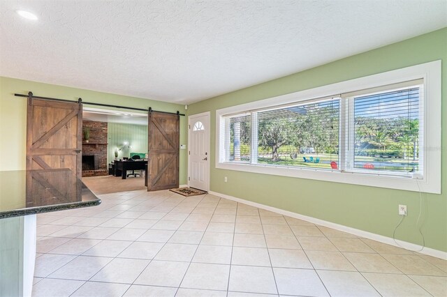 5311 36th Ave E, Palmetto, FL 34221 - empty room with a barn door, a textured ceiling, and light tile patterned flooring