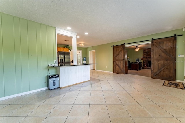 5311 36th Ave E, Palmetto, FL 34221 - unfurnished living room with a barn door, light tile patterned flooring, a textured ceiling, and recessed lighting