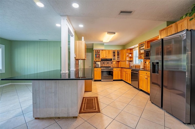 5311 36th Ave E, Palmetto, FL 34221 - kitchen featuring stainless steel appliances, a peninsula, dark countertops, light tile patterned floors, and a textured ceiling