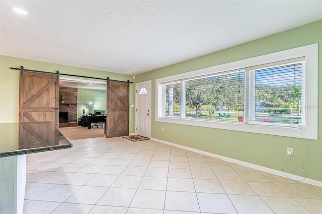 5311 36th Ave E, Palmetto, FL 34221 - empty room with a barn door, a textured ceiling, and light tile patterned flooring