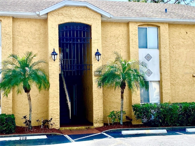 1959 Toucan Way Unit 206, Sarasota, FL 34232 - view of exterior entry with roof with shingles, stucco siding, and uncovered parking