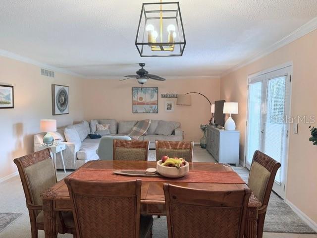 1959 Toucan Way Unit 206, Sarasota, FL 34232 - dining area featuring light carpet, crown molding, a ceiling fan, and a textured ceiling