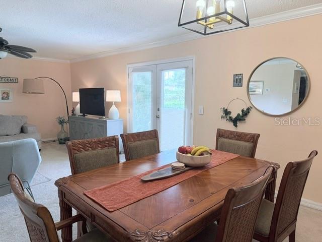 1959 Toucan Way Unit 206, Sarasota, FL 34232 - dining area featuring light colored carpet, ornamental molding, french doors, a chandelier, and a ceiling fan