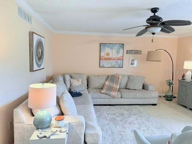 1959 Toucan Way Unit 206, Sarasota, FL 34232 - carpeted living room featuring crown molding and ceiling fan