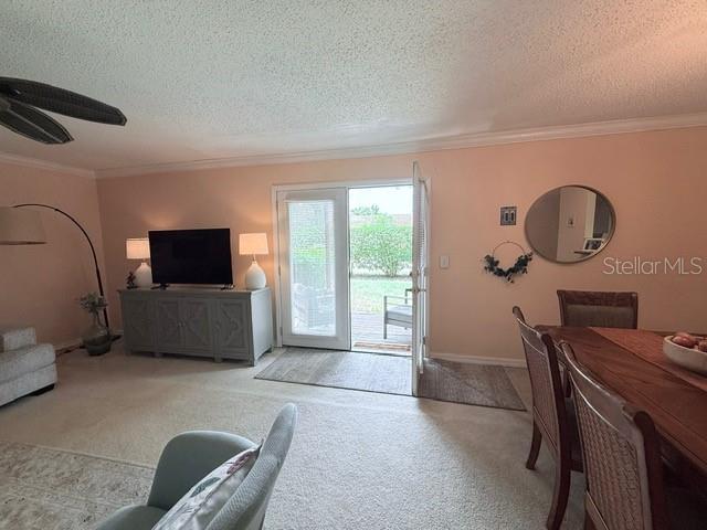 1959 Toucan Way Unit 206, Sarasota, FL 34232 - carpeted living room featuring a textured ceiling, crown molding, and a ceiling fan