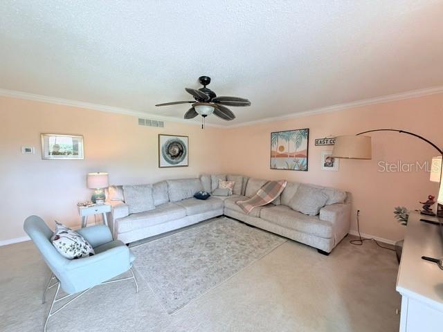 1959 Toucan Way Unit 206, Sarasota, FL 34232 - living room with crown molding, light carpet, and a ceiling fan