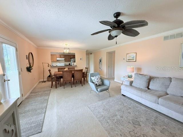 1959 Toucan Way Unit 206, Sarasota, FL 34232 - living room with ornamental molding, light carpet, ceiling fan, and a textured ceiling