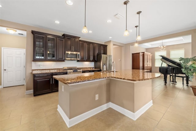 773 Rosemary Cir, Bradenton, FL 34212 - kitchen featuring appliances with stainless steel finishes, dark brown cabinetry, dark stone counters, a center island with sink, and recessed lighting