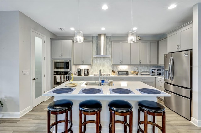 6219 Golden Nettle Dr, Apollo Beach, FL 33572 - kitchen featuring stainless steel appliances, wall chimney range hood, light wood-style flooring, light countertops, and tasteful backsplash