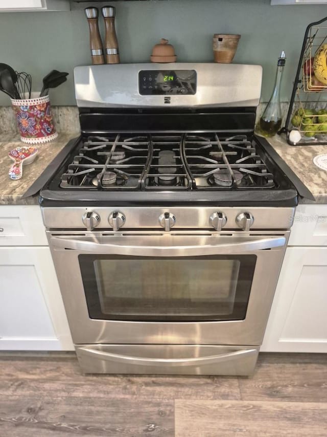 15917 Mercott Ct, Clermont, FL 34714 - kitchen view of gas stove, white cabinetry, and wood finished floors