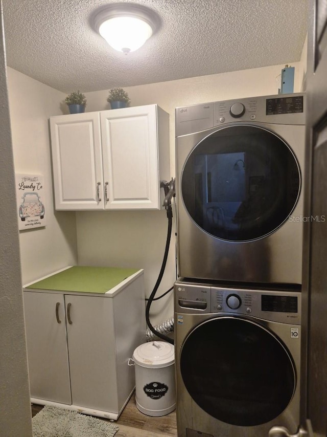15917 Mercott Ct, Clermont, FL 34714 - laundry area featuring cabinet space, stacked washing machine and dryer, a textured ceiling, and wood finished floors