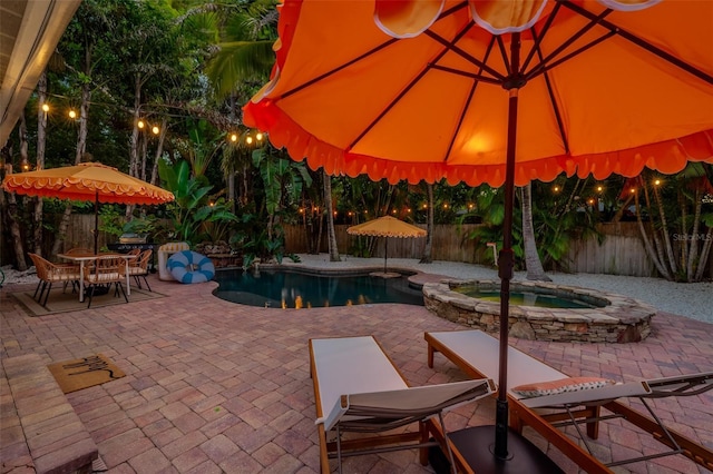 522 31st St W, Bradenton, FL 34205 - pool at night with a patio, a fenced backyard, and a pool with connected hot tub