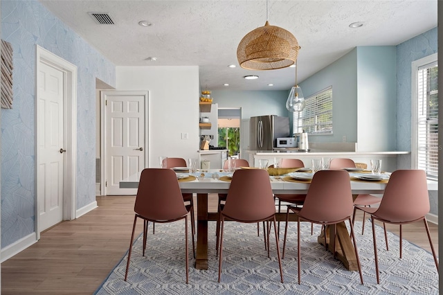522 31st St W, Bradenton, FL 34205 - dining room featuring healthy amount of natural light, wood finished floors, wallpapered walls, a textured ceiling, and recessed lighting