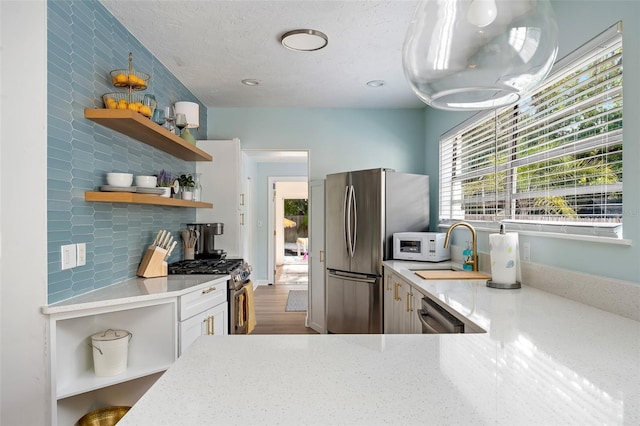 522 31st St W, Bradenton, FL 34205 - kitchen featuring open shelves, stainless steel appliances, tasteful backsplash, wood finished floors, and light stone countertops