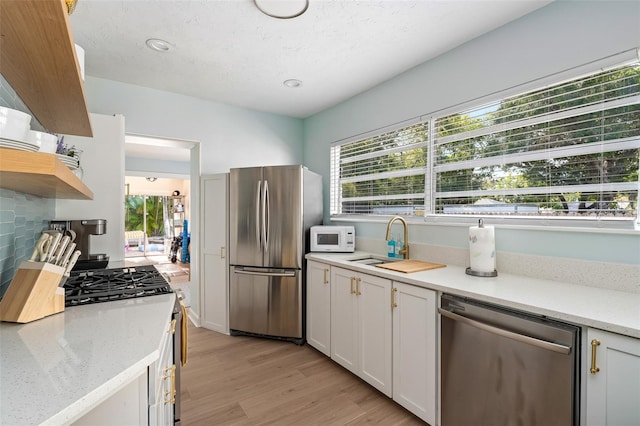 522 31st St W, Bradenton, FL 34205 - kitchen featuring appliances with stainless steel finishes, white cabinets, light wood-type flooring, open shelves, and light stone countertops