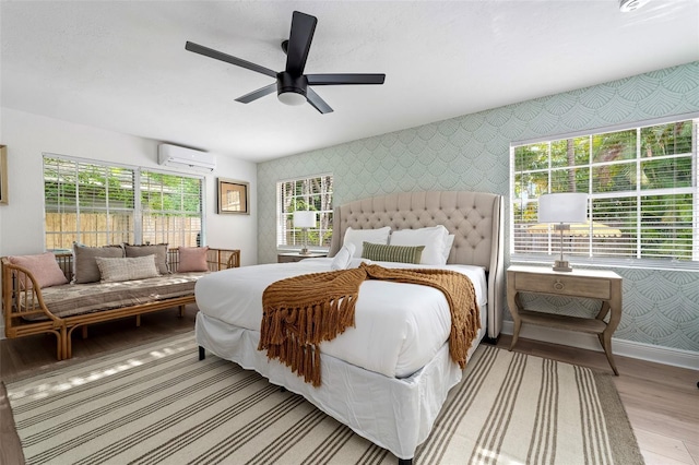 522 31st St W, Bradenton, FL 34205 - bedroom with wallpapered walls, a wall unit AC, wood finished floors, ceiling fan, and an accent wall