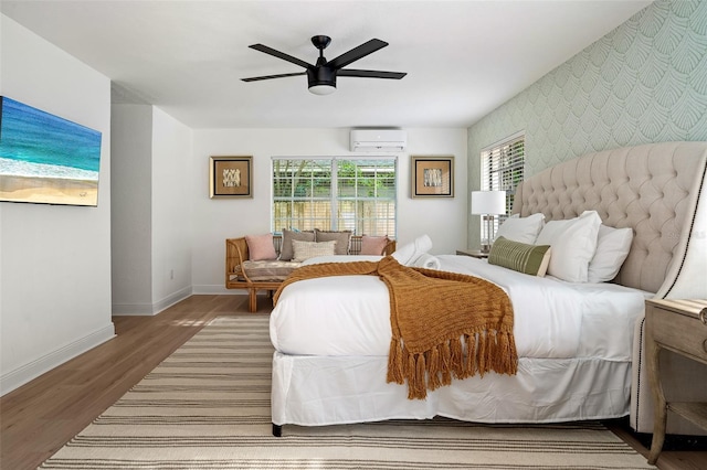 522 31st St W, Bradenton, FL 34205 - bedroom with an AC wall unit, an accent wall, wallpapered walls, wood finished floors, and ceiling fan