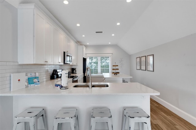 538 Canal Rd, Sarasota, FL 34242 - kitchen featuring stainless steel microwave, range with electric cooktop, a peninsula, light wood-type flooring, and backsplash