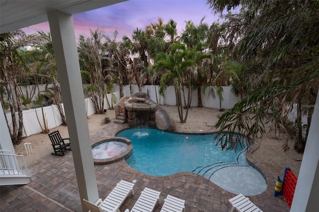 538 Canal Rd, Sarasota, FL 34242 - pool at dusk featuring a pool with connected hot tub, a patio, and a fenced backyard