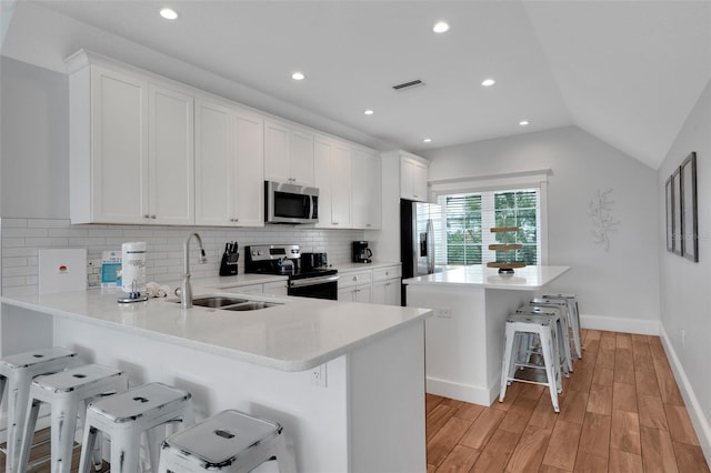538 Canal Rd, Sarasota, FL 34242 - kitchen featuring stainless steel appliances, a kitchen bar, tasteful backsplash, light wood finished floors, and light countertops