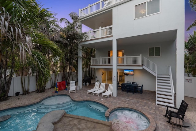 538 Canal Rd, Sarasota, FL 34242 - back of property at dusk with stairway, a fenced backyard, a balcony, a patio area, and stucco siding