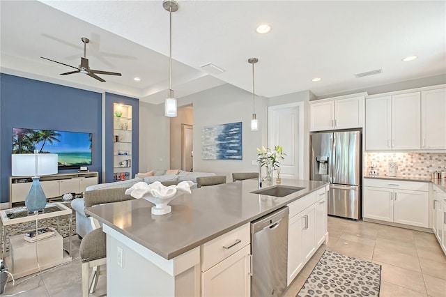 7983 Sandstar Way, Sarasota, FL 34240 - kitchen featuring appliances with stainless steel finishes, open floor plan, a center island with sink, backsplash, and light tile patterned flooring