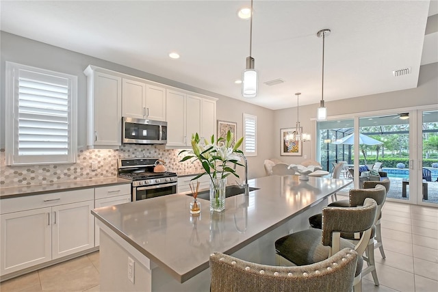 7983 Sandstar Way, Sarasota, FL 34240 - kitchen featuring stainless steel appliances, light tile patterned floors, a kitchen breakfast bar, tasteful backsplash, and a kitchen island with sink