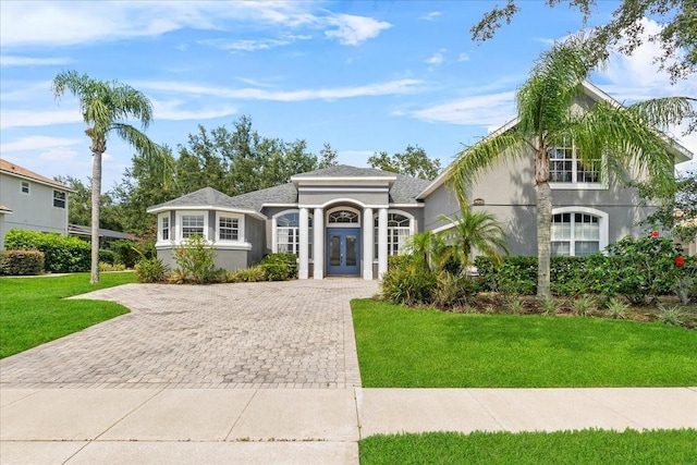 4013 Greystone Dr, Clermont, FL 34711 - mediterranean / spanish home featuring french doors, decorative driveway, a front lawn, and stucco siding