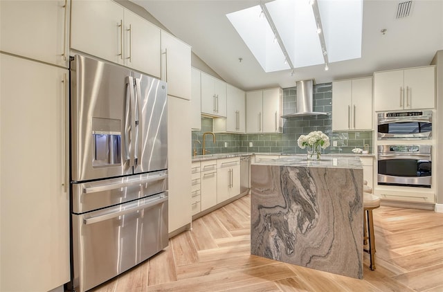 2103 Harbourside Dr Unit 1102, Longboat Key, FL 34228 - kitchen featuring appliances with stainless steel finishes, wall chimney range hood, a skylight, light stone countertops, and vaulted ceiling