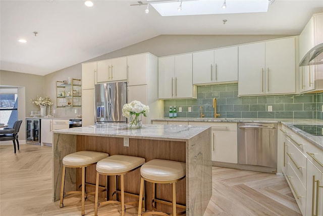 2103 Harbourside Dr Unit 1102, Longboat Key, FL 34228 - kitchen with stainless steel appliances, a skylight, lofted ceiling, beverage cooler, and a kitchen island