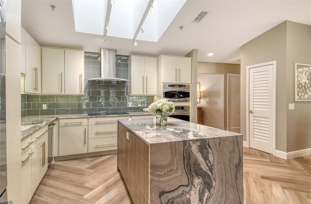 2103 Harbourside Dr Unit 1102, Longboat Key, FL 34228 - kitchen featuring wall chimney range hood, a skylight, tasteful backsplash, a kitchen island, and recessed lighting