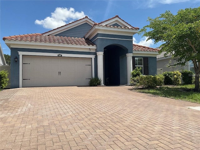 4428 Conchfish Ln, Osprey, FL 34229 - mediterranean / spanish house featuring decorative driveway, an attached garage, stucco siding, and a tiled roof