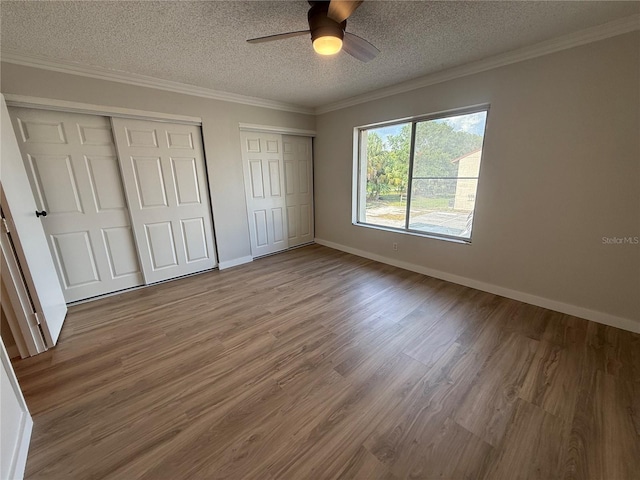 2613 Pine Lake Ter Unit C, Sarasota, FL 34237 - unfurnished bedroom with two closets, a textured ceiling, wood finished floors, crown molding, and ceiling fan
