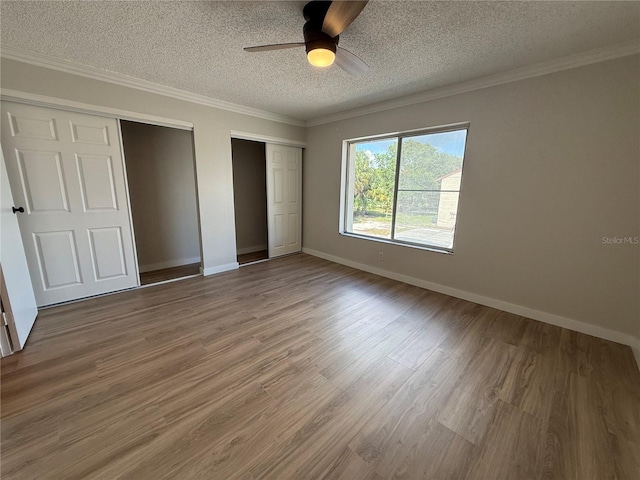 2613 Pine Lake Ter Unit C, Sarasota, FL 34237 - unfurnished bedroom featuring two closets, a textured ceiling, wood finished floors, a ceiling fan, and ornamental molding