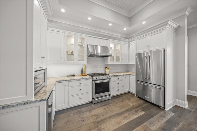 5569 Cape Leyte Dr, Sarasota, FL 34242 - kitchen with premium appliances, wall chimney range hood, recessed lighting, a tray ceiling, and white cabinetry