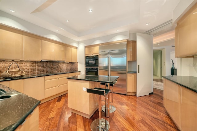 990 Blvd Of The Arts Unit 801, Sarasota, FL 34236 - kitchen with built in refrigerator, a raised ceiling, tasteful backsplash, a breakfast bar, and light wood-type flooring