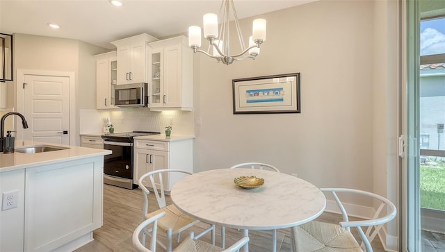 491 Daylily Blvd, Nokomis, FL 34275 - kitchen featuring stainless steel appliances, light wood finished floors, decorative backsplash, white cabinets, and glass insert cabinets