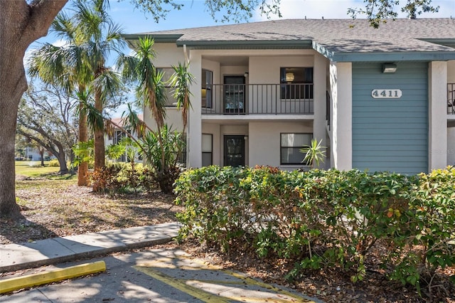 4411 46th Ave W Unit 201, Bradenton, FL 34210 - view of front facade with a shingled roof, stucco siding, uncovered parking, and a balcony