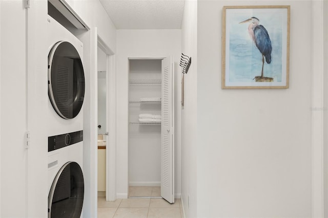 4411 46th Ave W Unit 201, Bradenton, FL 34210 - laundry room featuring stacked washing machine and dryer, light tile patterned floors, and a textured ceiling
