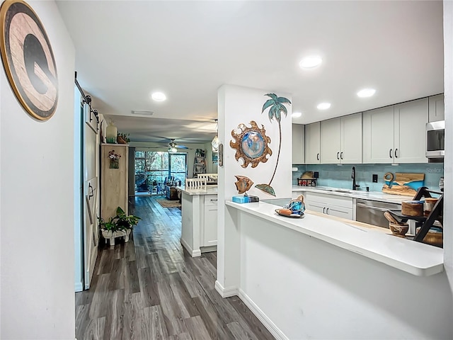 3700 S Osprey Ave Unit 122, Sarasota, FL 34239 - kitchen featuring stainless steel appliances, dark wood-style flooring, a barn door, light countertops, and backsplash