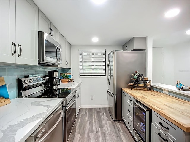 3700 S Osprey Ave Unit 122, Sarasota, FL 34239 - kitchen featuring appliances with stainless steel finishes, butcher block countertops, beverage cooler, wood finished floors, and recessed lighting