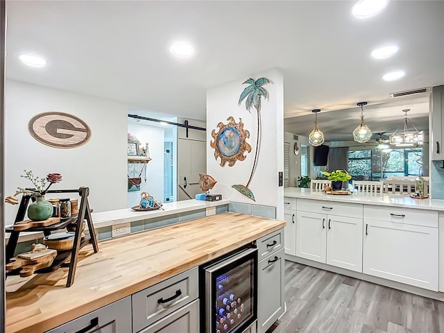 3700 S Osprey Ave Unit 122, Sarasota, FL 34239 - kitchen featuring wood counters, wine cooler, a barn door, a peninsula, and light wood finished floors