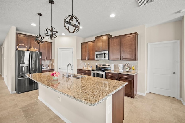 226 Tapa Parish Run, Bradenton, FL 34212 - kitchen with stainless steel appliances, a kitchen island with sink, tasteful backsplash, light stone countertops, and a textured ceiling