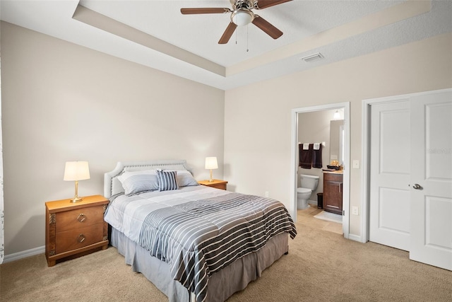 226 Tapa Parish Run, Bradenton, FL 34212 - bedroom with light carpet, a tray ceiling, connected bathroom, and ceiling fan