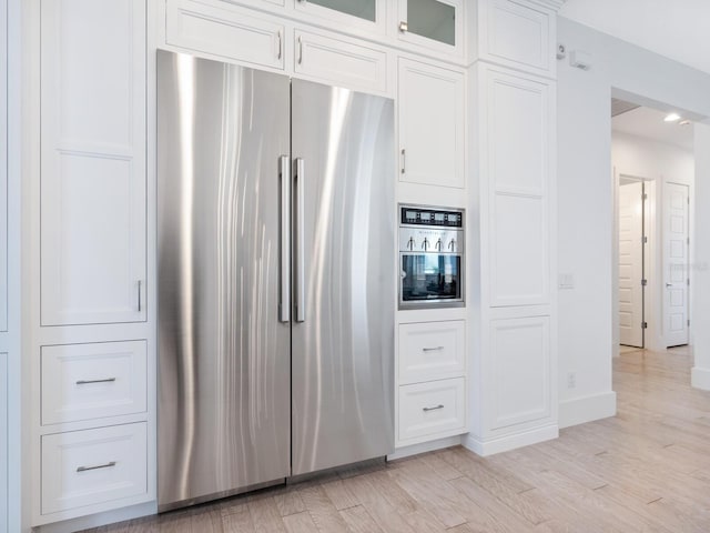 5630 Inspiration Ter, Bradenton, FL 34210 - kitchen with stainless steel fridge, white cabinets, light wood-type flooring, and glass insert cabinets